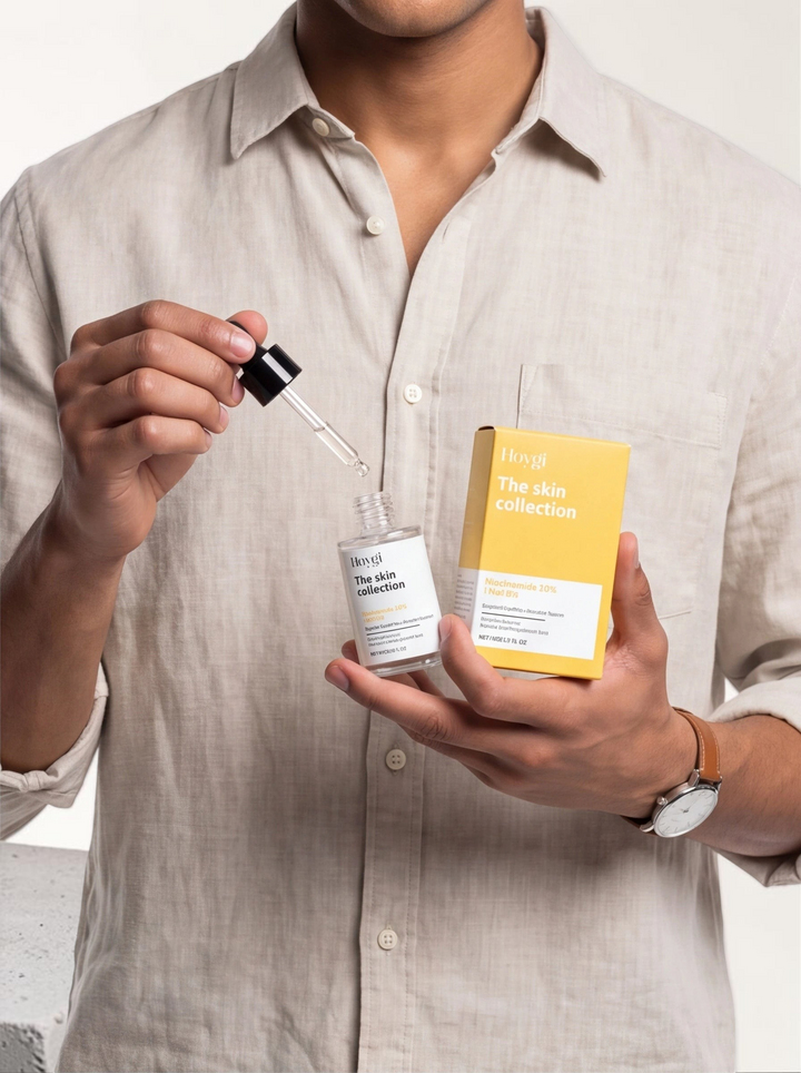 TheGromify Nicotinamide Brightening Face Serum bottle and yellow box held by a man in a beige linen shirt